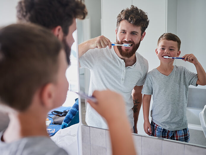 father and son brushing their teeth together