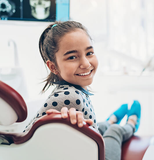 smiling young girl sitting in a dental chair