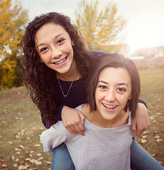 two smiling sisters wearing braces