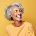 Gray-haired woman in a yellow blouse smiling