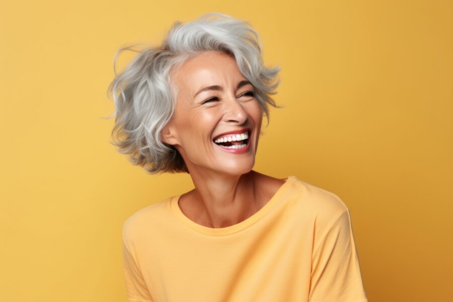 Gray-haired woman in a yellow blouse smiling