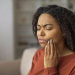 woman touching her jaw in pain