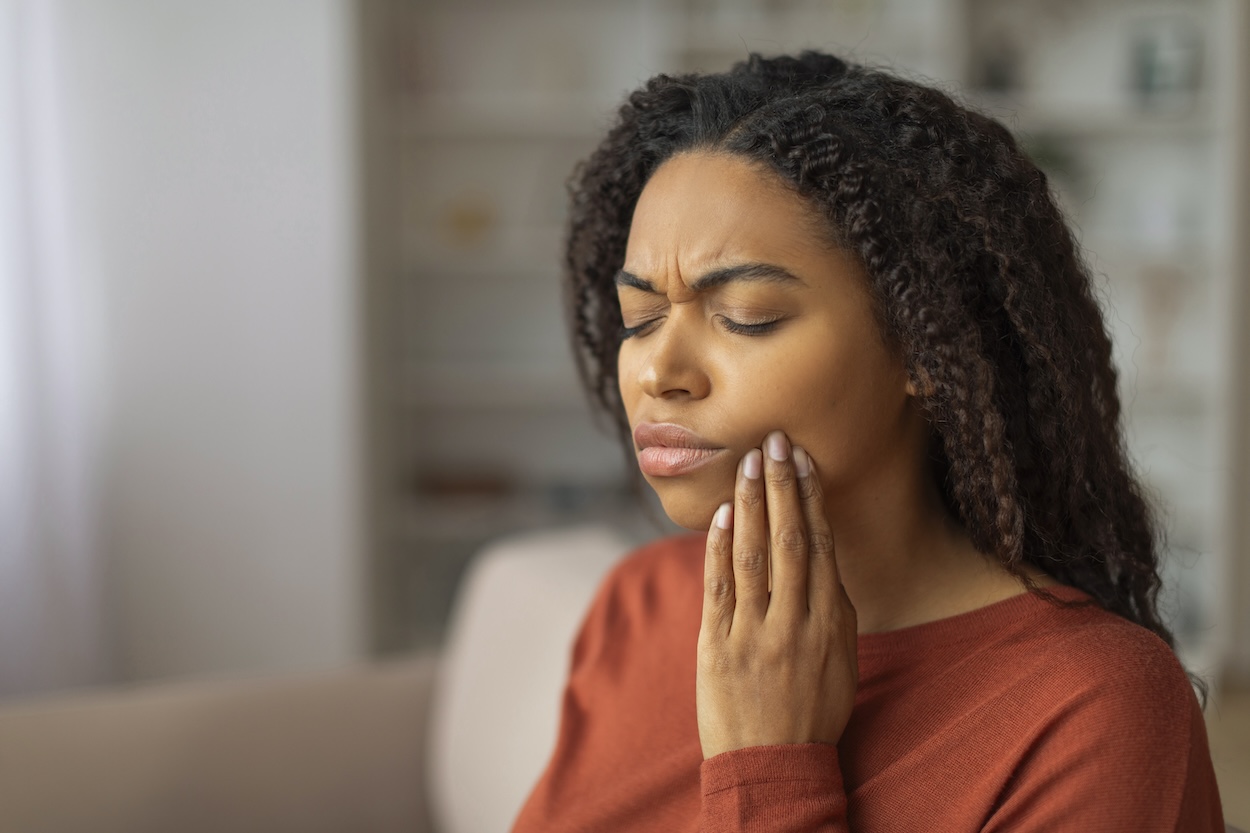 woman touching her jaw in pain